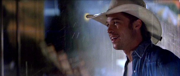 Brad Pitt as the cowboy, in hat, standing in the rain outside motel room door.
