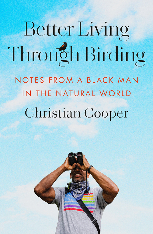 Better Living Through Birding by Christian Cooper book cover. Author is shown looking to the sky with binoculars, wearing a T-shirt with a pride flag emblem, against a background of a blue sky with fluffy white clouds.
